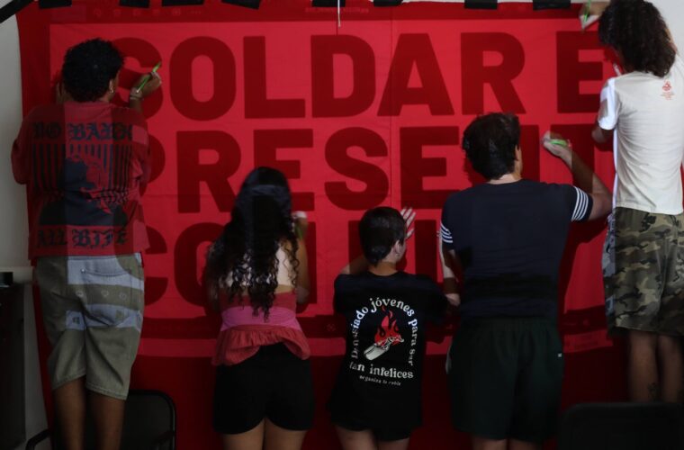 Un grupo de militantes prepara una pancarta sobre la Universidad de Jóvenes Marxistas