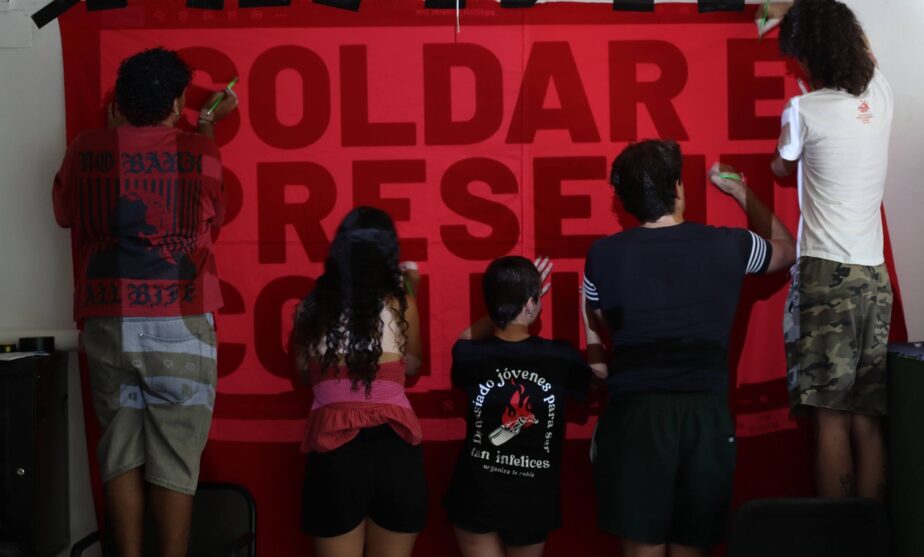 Un grupo de militantes prepara una pancarta sobre la Universidad de Jóvenes Marxistas