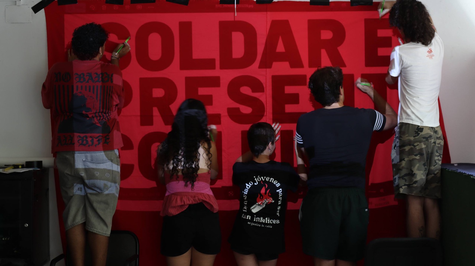 Un grupo de militantes prepara una pancarta sobre la Universidad de Jóvenes Marxistas